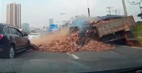 بالفيديو والصور.. حمولة طوب أحمر تدفن سيارة على الطريق بالصين