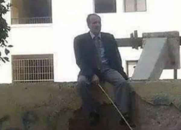 مدير مدرسة يجلس على السور بعصا لمنع التلاميذ من الهروب!