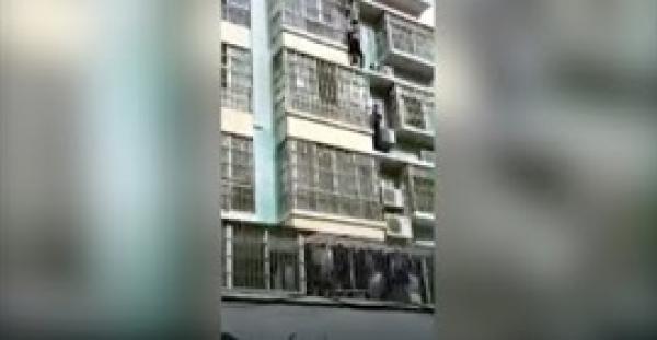 رجلان يتسلقان مبنى لإنقاذ طفل يتدلى من مبنى في مشهد بطولي (فيديو)