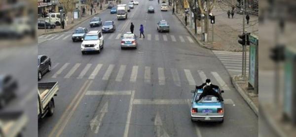 شرطى صينى على ظهر سيارة أجرة لملاحقة قائدها والقبض عليه