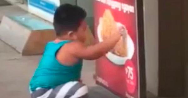 بالفيديو: طفل جائع يحاول تناول الدجاج من ملصق إعلاني