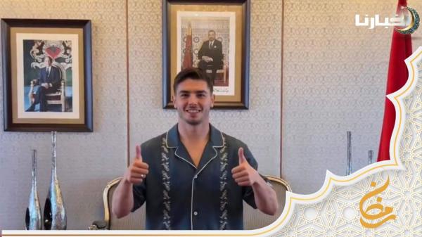 إبراهيم دياز يلتقط صورا تذكارية إلى جانب صورة الملك محمد السادس لدى وصوله مطار الرباط