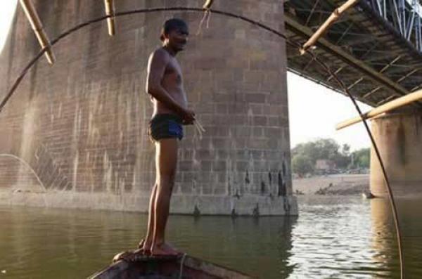 فقراء يصطادون العملة الهندية في نهر يامونا