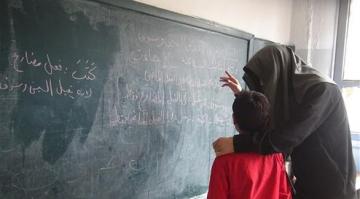  صورة الداعشي يعلم طفلاً أن كتب فعل مضارع (تويتر) 