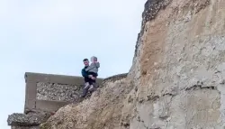 رجل يخاطر بحياة طفلته من أجل صورة على حافة جرف خطير