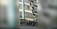 رجلان يتسلقان مبنى لإنقاذ طفل يتدلى من مبنى في مشهد بطولي (فيديو)
